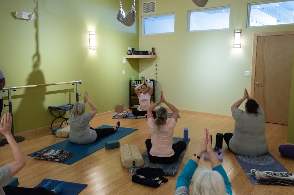 Seated yoga class with arms raised overhead at Serenity Yoga & Pilates Studio in Iowa City